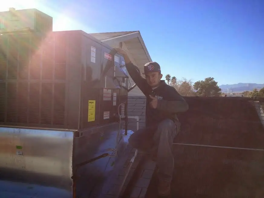 HVAC technician performing Air Duct Cleaning on a rooftop unit in Milton